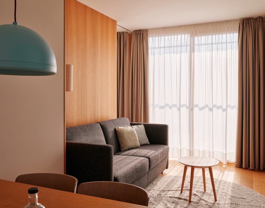 A chic modern living space with a plush couch, a sleek table, and a window that offers a view outside.
